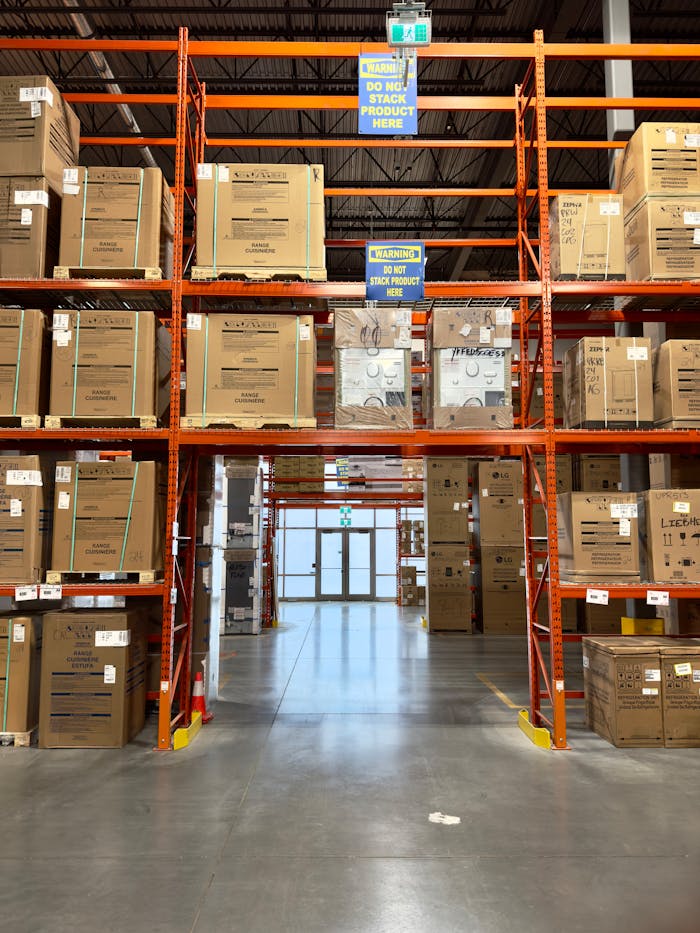 about-02 Large warehouse interior with racks filled with cardboard boxes, offering ample storage space.